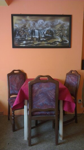 A dining area with a table set for two, featuring chairs with a marbled pattern upholstery and a framed landscape painting above. - Pension Lada (Karlovy Vary)