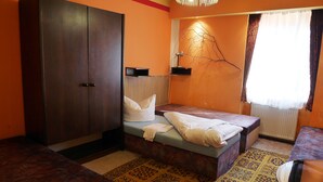 A room with a bed, a wardrobe, a small table, and a decorative wall piece. - Pension Lada (Karlovy Vary)