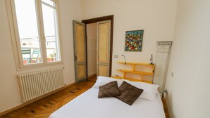 Een slaapkamer met een bed, een radiator, een raam en een deur naar buiten.