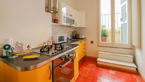 Een kleine keuken met een magnetron, fornuis en spoelbak. Er is een raam met uitzicht op het omliggende landschap.