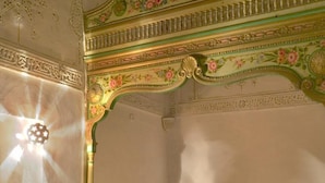A room with a bed, a round table with fruit, and a decorative ceiling. - Dar Hayder (Tunis)