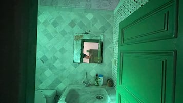 Een badkamer met een wastafel, toilet en groene kastjes.