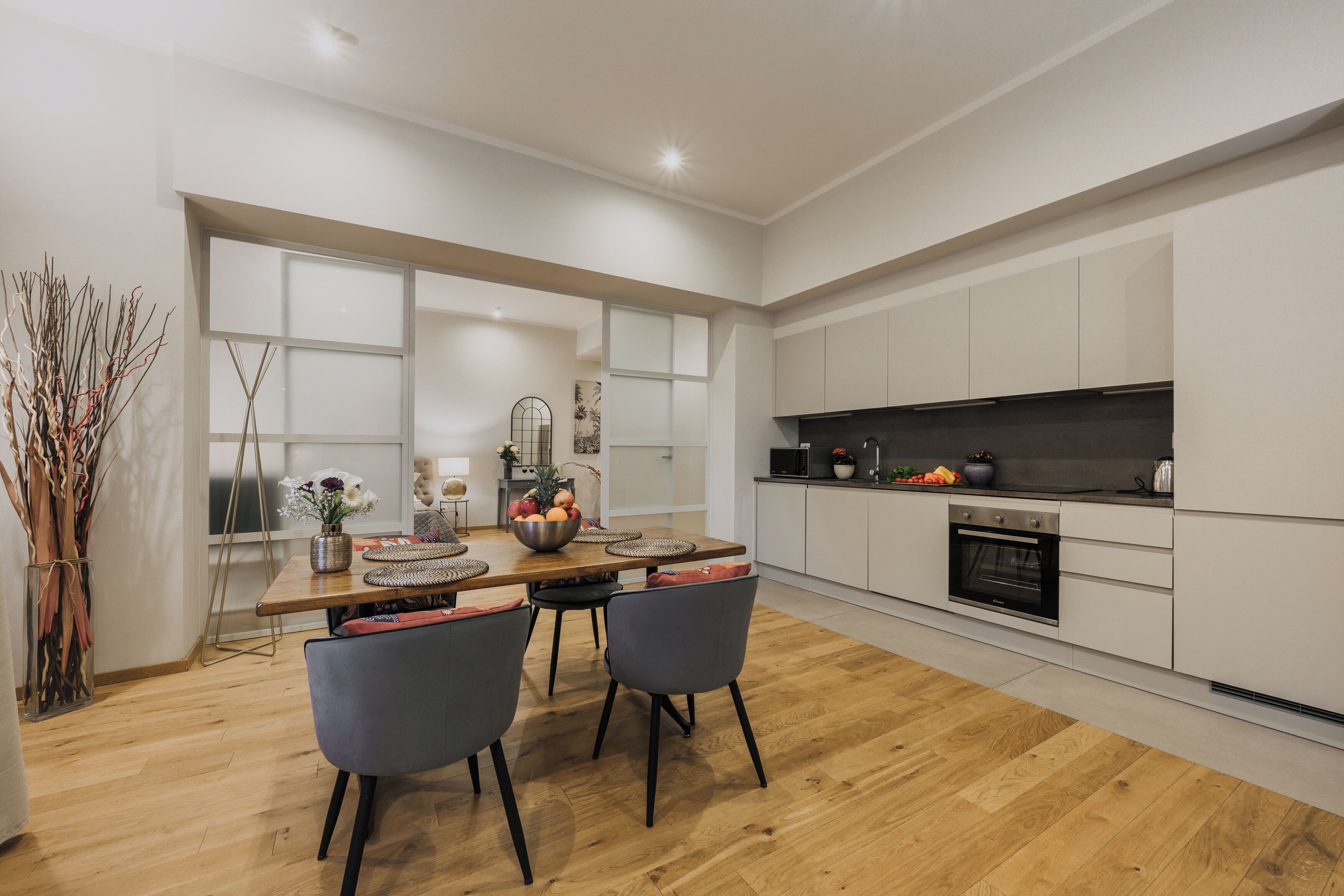 A modern kitchen with white cabinets, a wooden countertop, and a dining area with a table and chairs.