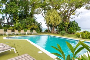 Una piscina al aire libre, sillones reclinables de piscina