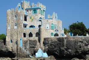 A castle-like building with multiple levels, arched windows, and a prominent tower. - Blue Cave Castles (Negril)