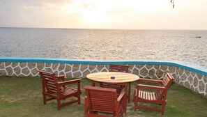 A patio with a round wooden table and four wooden chairs, overlooking a body of water. - Blue Cave Castles (Negril)
