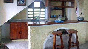 Una cocina con armarios de madera, un lavabo y dos taburetes.