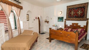 Una habitación con cama, cabecera de madera, alfombra estampada y tapiz colgado en la pared.