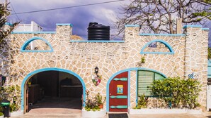 Un edificio de piedra con arcos en las puertas y un depósito de agua en el techo.