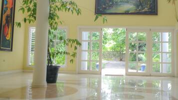 A spacious lobby with a large potted plant, a painting on the wall, and a view through the glass doors.