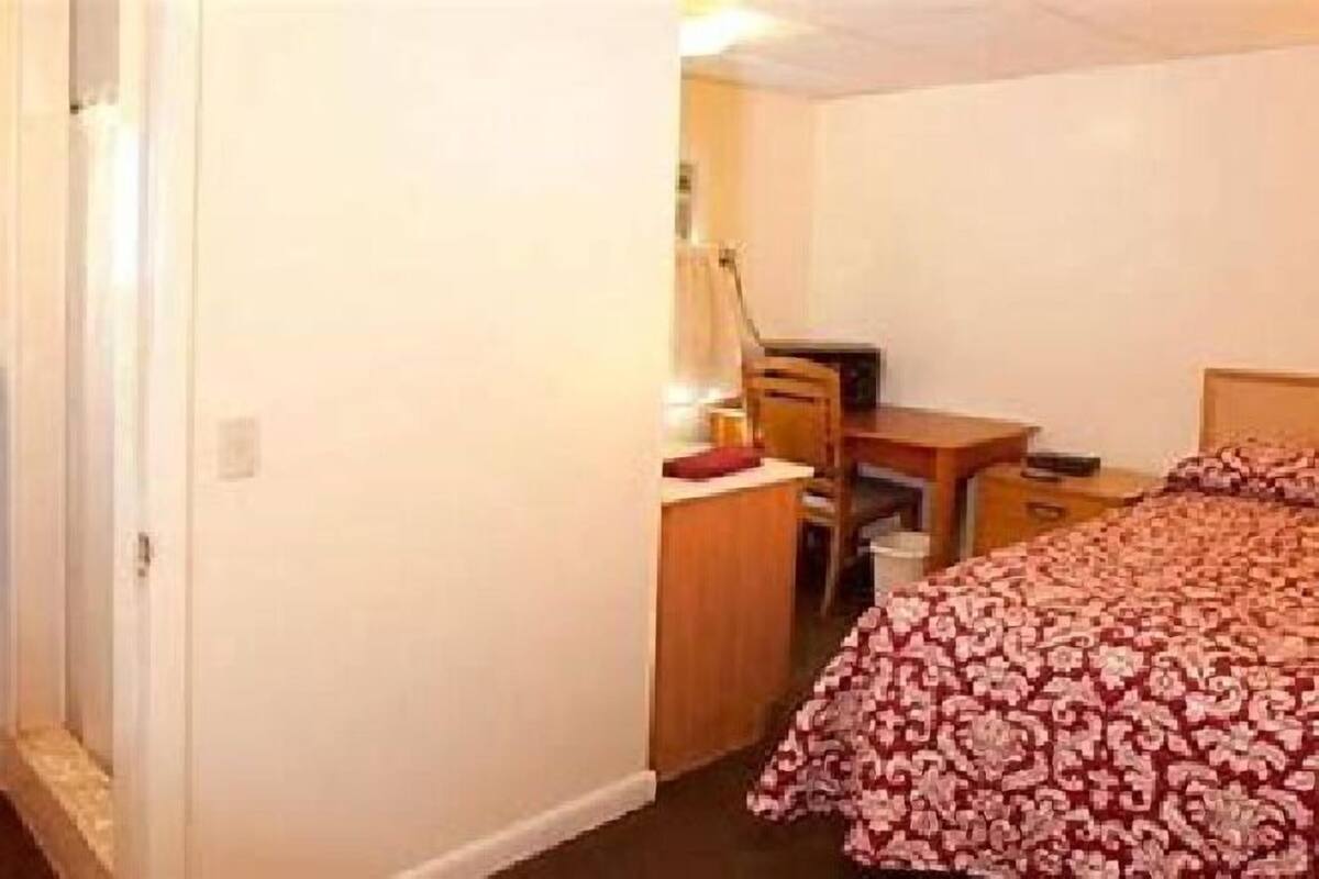 A hotel room with a bed, a desk, a chair, and a nightstand.