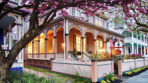 A historic building with a porch, ornate columns, and a sign indicating it is a bed and breakfast.