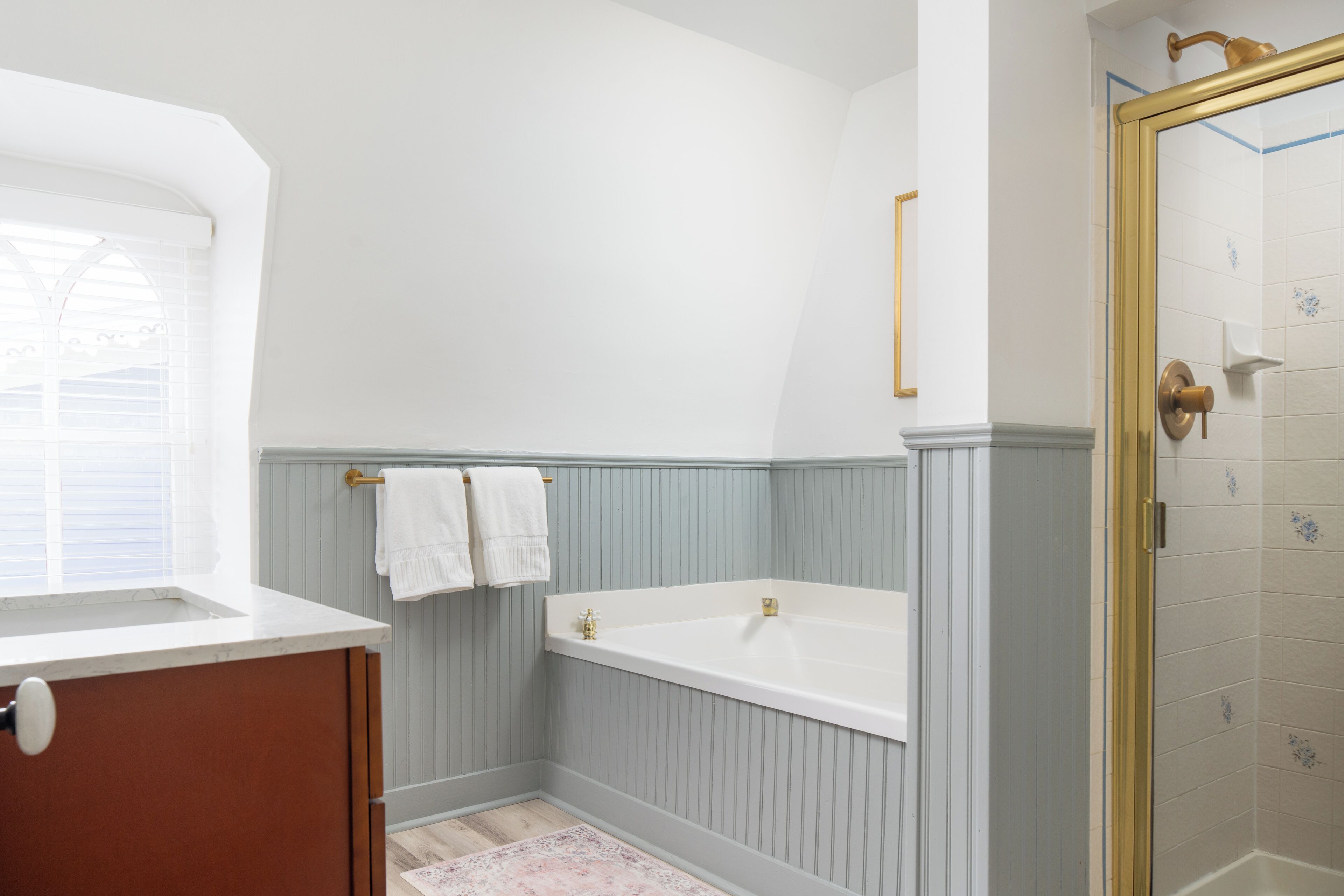 A bathroom with a bathtub, a window, and a shower area.