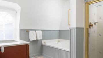 A bathroom with a bathtub, a window, and a shower area.