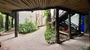 A covered outdoor area with a brick pathway, wooden beams, and potted plants. - Casa Caribe Cancun (Cancun)
