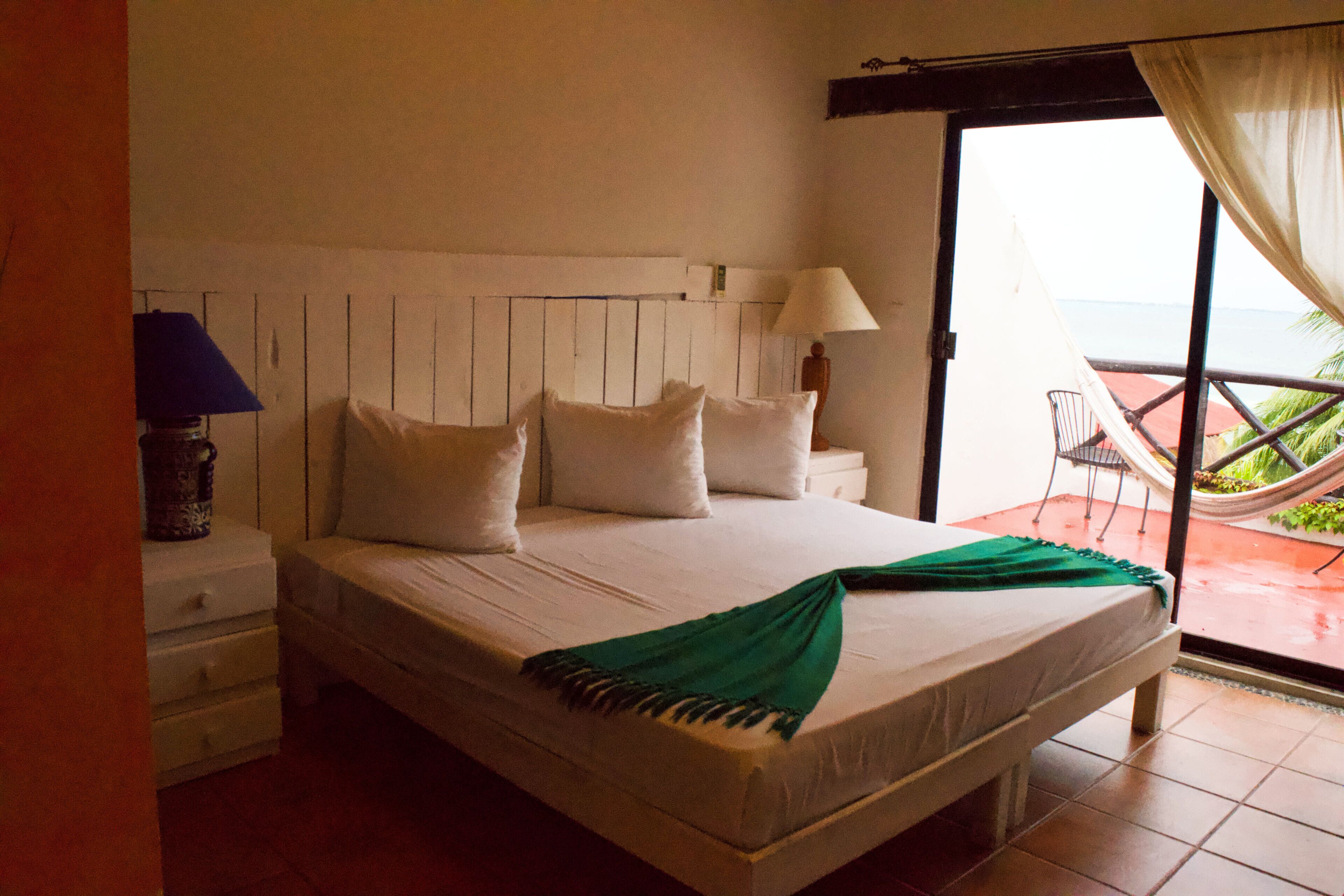 Un dormitorio con cama, mesita de noche, lámpara y vistas al exterior.