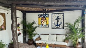 A cozy outdoor seating area with a wooden bench, a cushioned sofa, and potted plants. - Casa Caribe Cancun (Cancun)