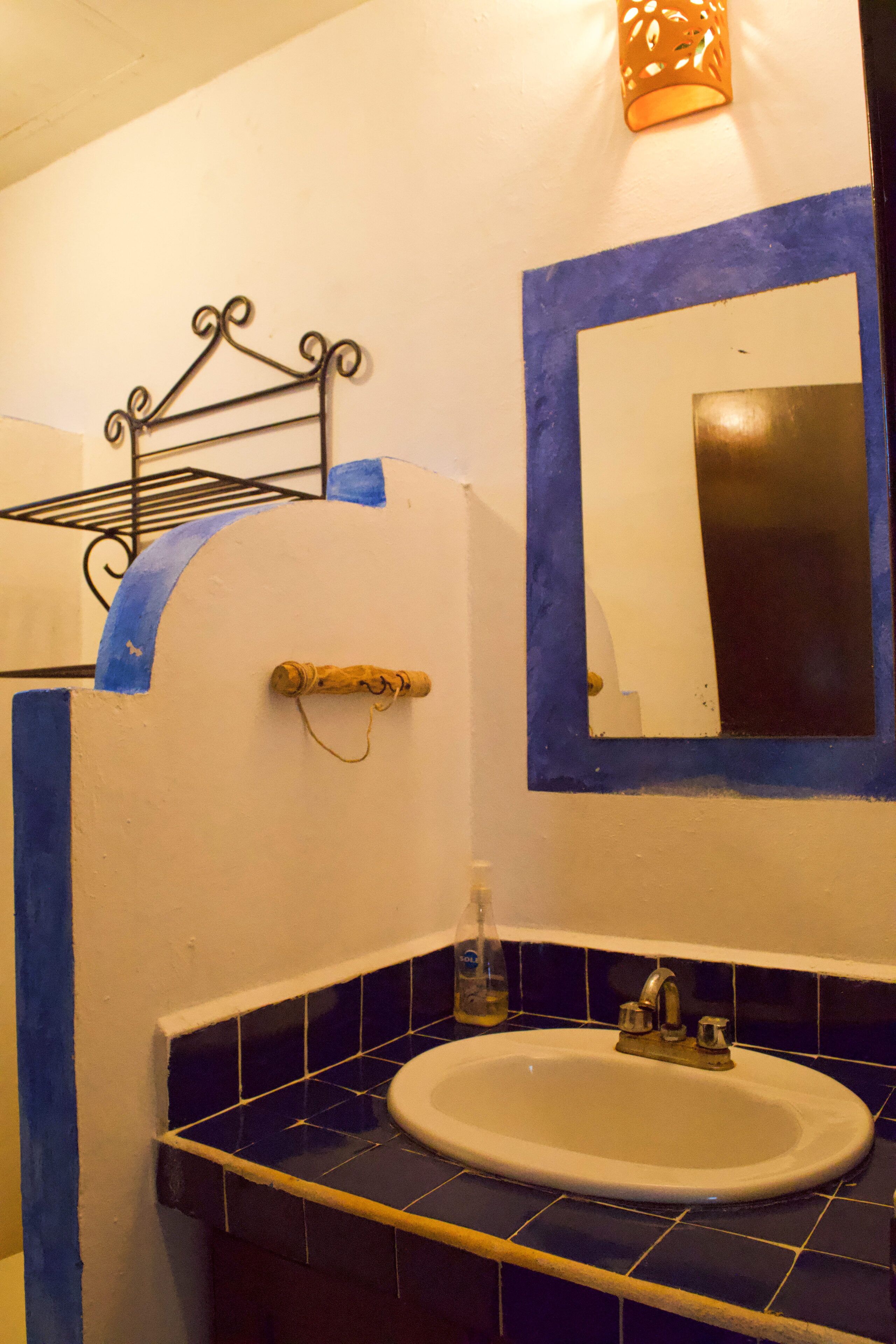 A bathroom with a sink, mirror, and towel rack.