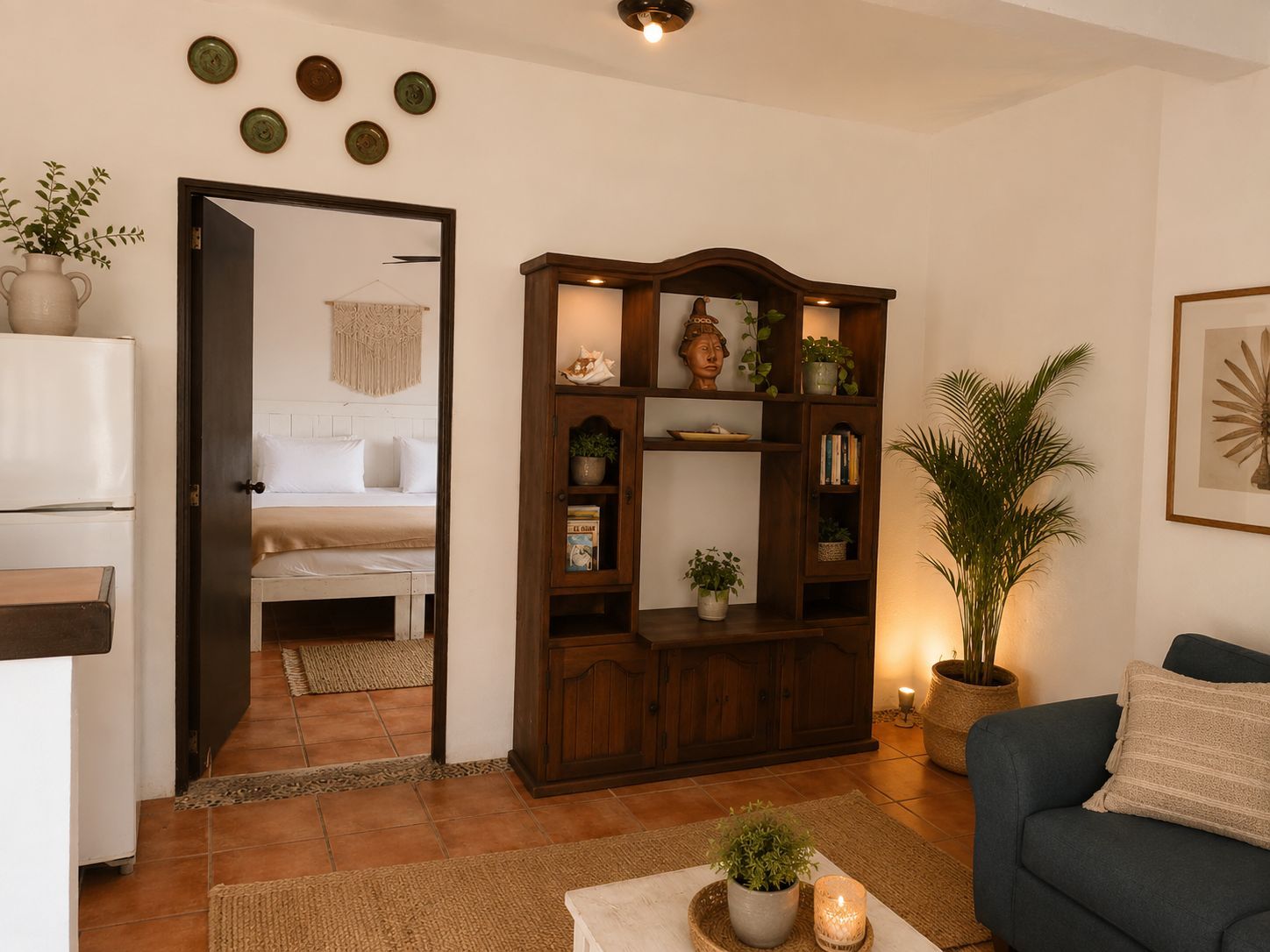 Ein gemütliches Wohnzimmer mit einer Couch, einem Couchtisch mit einer Pflanze, einem Bücherregal und einer Tür zu einem Schlafzimmer.