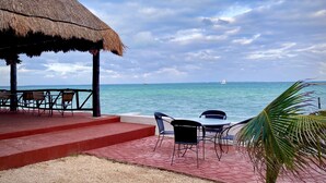 A beachside patio with a thatched roof, outdoor seating, and a view of the ocean. - Casa Caribe Cancun (Cancun)