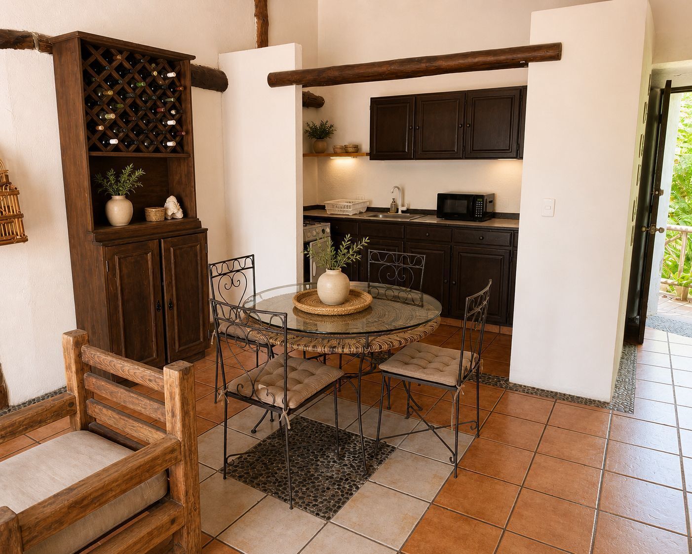 A compact kitchen with dark wooden cabinets, a round dining table with four chairs, and a built-in wine rack.