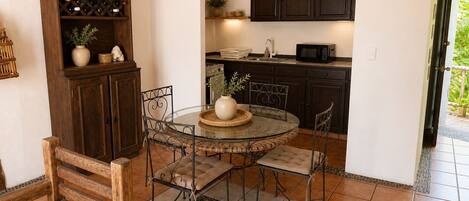 A compact kitchen with dark wooden cabinets, a round dining table with four chairs, and a built-in wine rack.