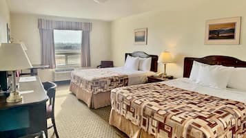 A hotel room with two beds, a desk, a chair, a window with curtains, a painting on the wall, and a ceiling light.