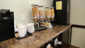 A breakfast bar with cereal dispensers, a coffee machine, and a refrigerator labeled "COLD ITEMS". - Prairie Moon Inn & Suites Unity (Unity)