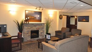 A lobby with a fireplace, seating area, and a desk with a computer. - Prairie Moon Inn & Suites Unity (Unity)