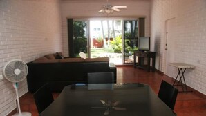 A room with a glass table, black chairs, a white fan, a sofa, and a TV. - Casa Moises (Mazatlán)