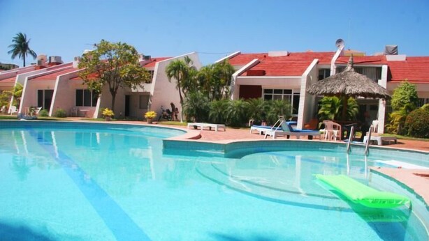 A swimming pool with lounge chairs and a thatched-roof structure. - Casa Moises (Mazatlán)
