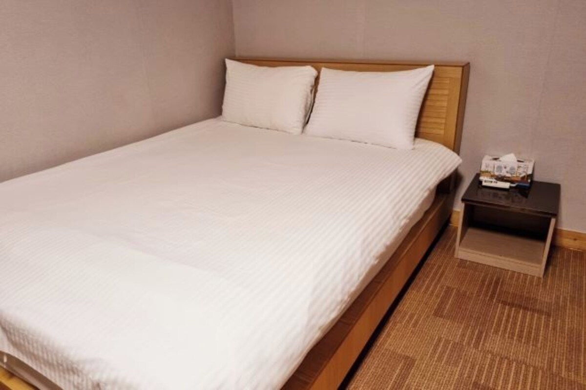 A neatly made bed with a wooden headboard and white bedding in a hotel room.