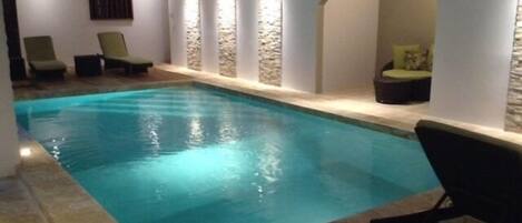 Una piscina al aire libre, sillones reclinables de piscina