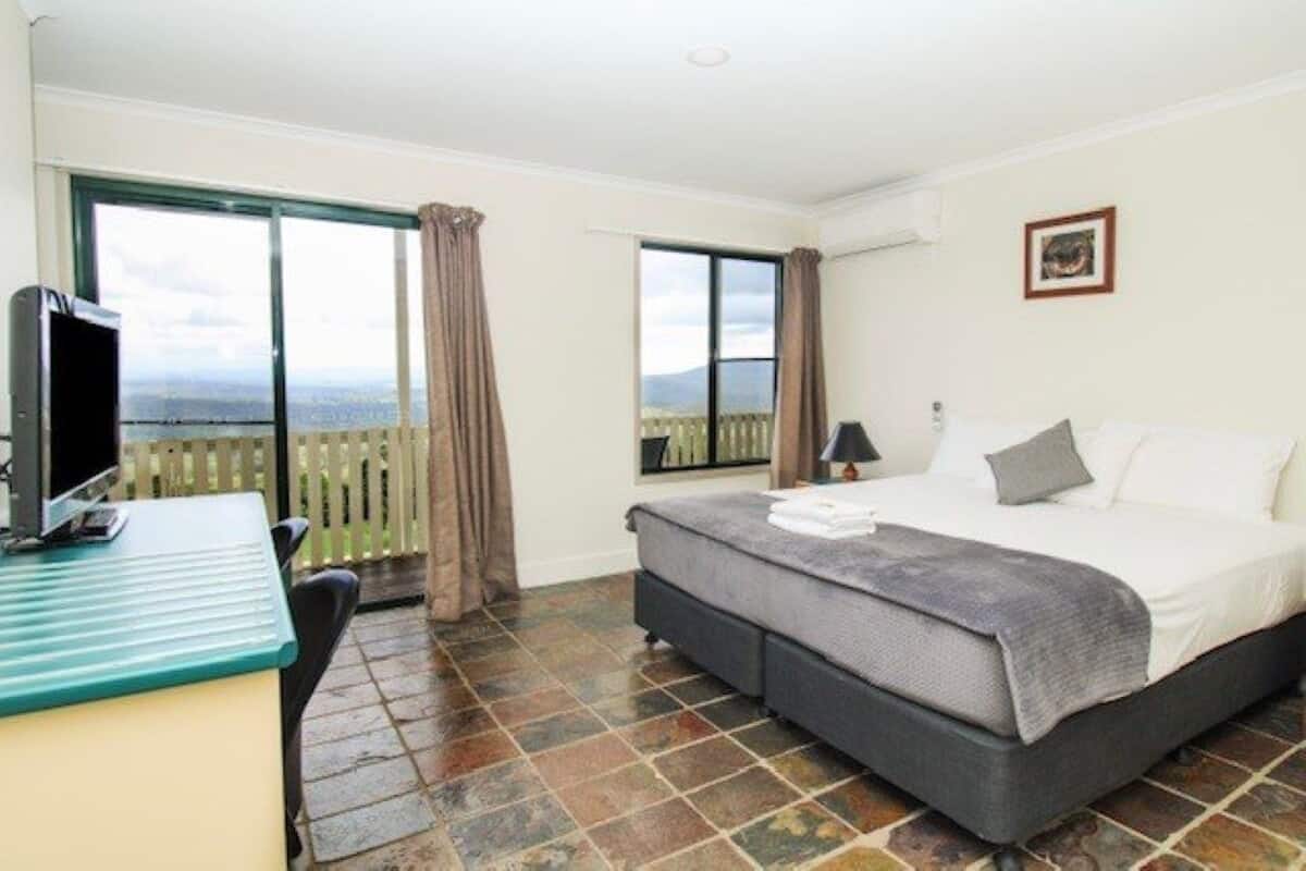 Ein Schlafzimmer mit Bett, Schreibtisch und Blick ins Freie.