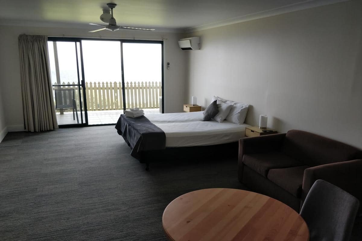 Ein Hotelzimmer mit Bett, einer Couch, einem Holztisch und einem Balkon mit weißem Zaun.