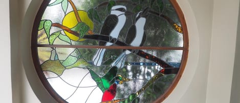 Uma janela de vitrais circular com pássaros e um sol.