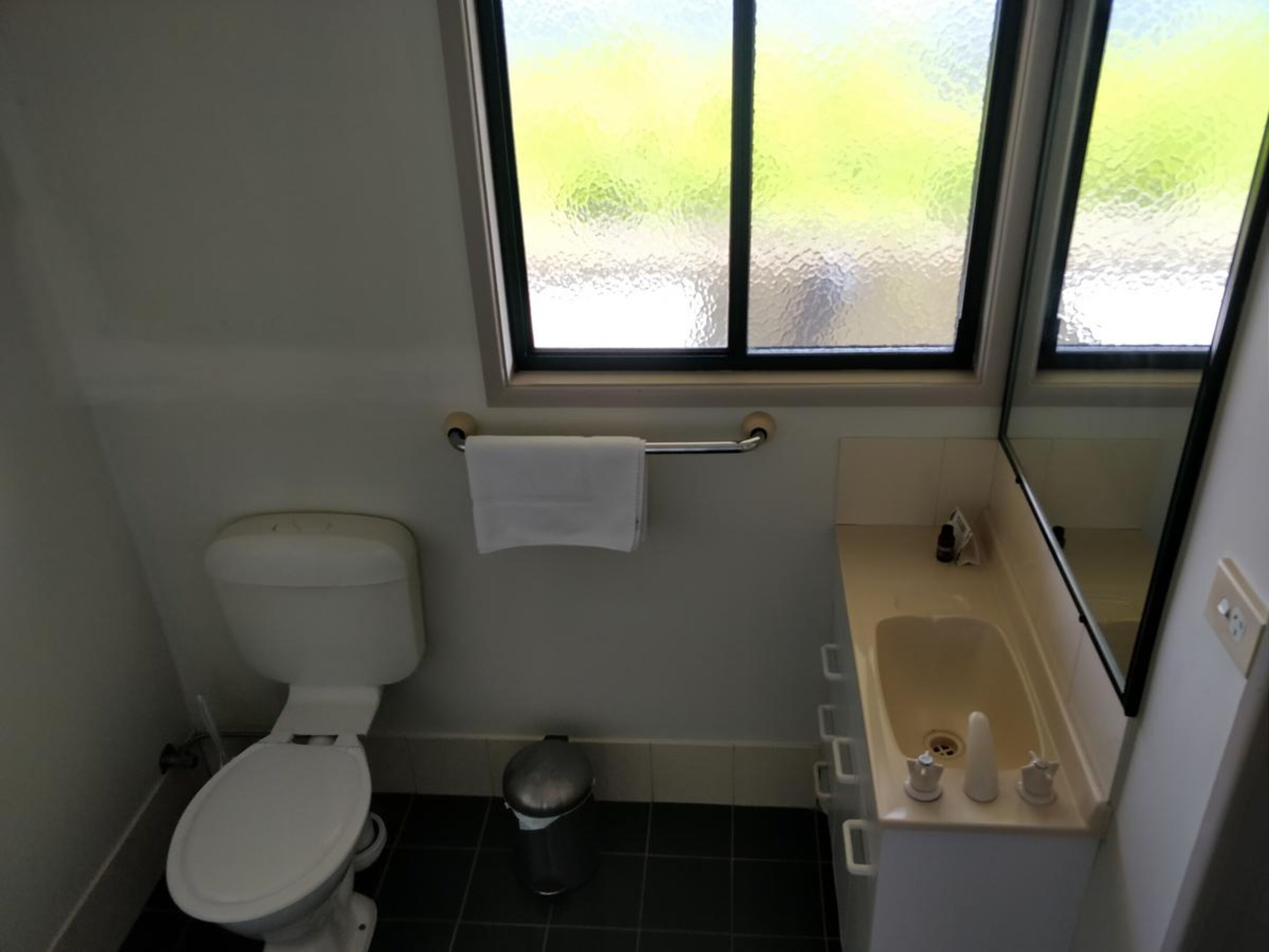 Ein kleines Badezimmer mit Toilette, Waschbecken und Fenster.