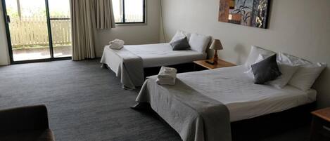 Et hotelværelse med to senge, en ventilator i loftet, et billede på væggen og udsigt til det fri gennem vinduet.