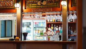 Een bar met een biertappunt, glazen die hangen en een bord waarop 'Irish Bar' staat.