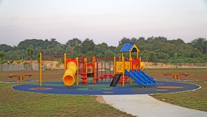 A playground with a slide, climbing structures, and a yellow tube slide. - CVR Homestay Melaka (Jasin)