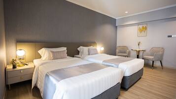 A hotel room with two beds, a small table, and two chairs.