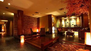 A lobby with a stone wall, seating area, and a reception desk with lockers. - S.D. Avenue Hotel (Bangkok)