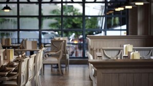 A restaurant with a long counter and high, arched windows. Tables are set with chairs and candles. - S.D. Avenue Hotel (Bangkok)