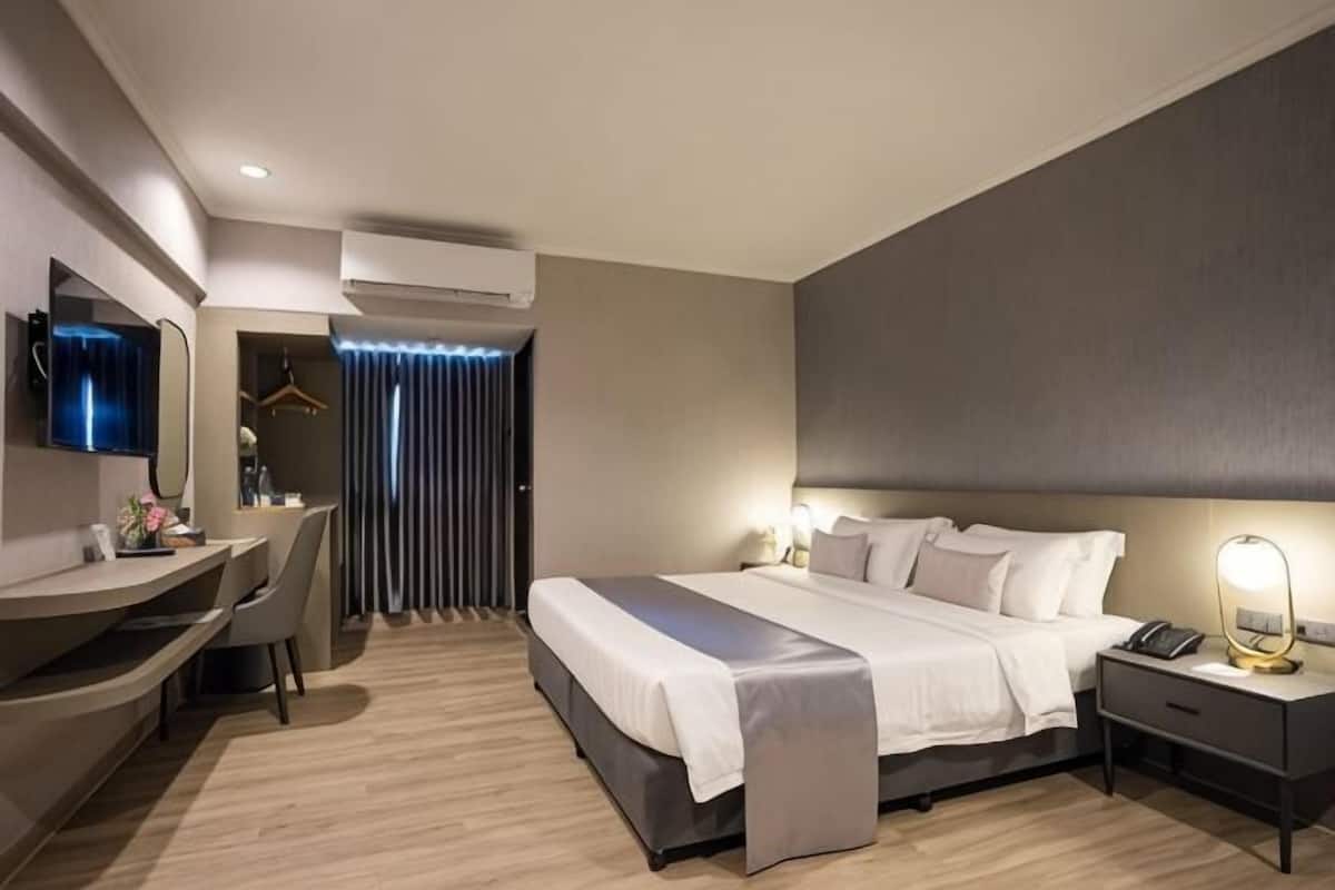 A modern hotel room with a bed, bedside table, desk, and chair.