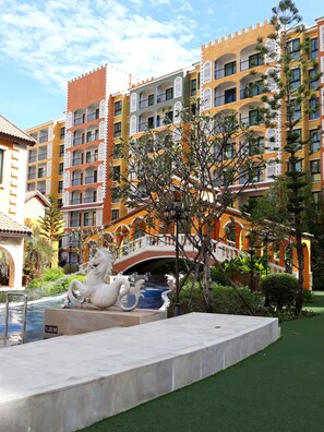 Un hotel con varios balcones, una fuente central y un puente que conecta los edificios.
