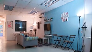 Una sala de estar moderna con un sofá, una mesita, un ventilador y un televisor.