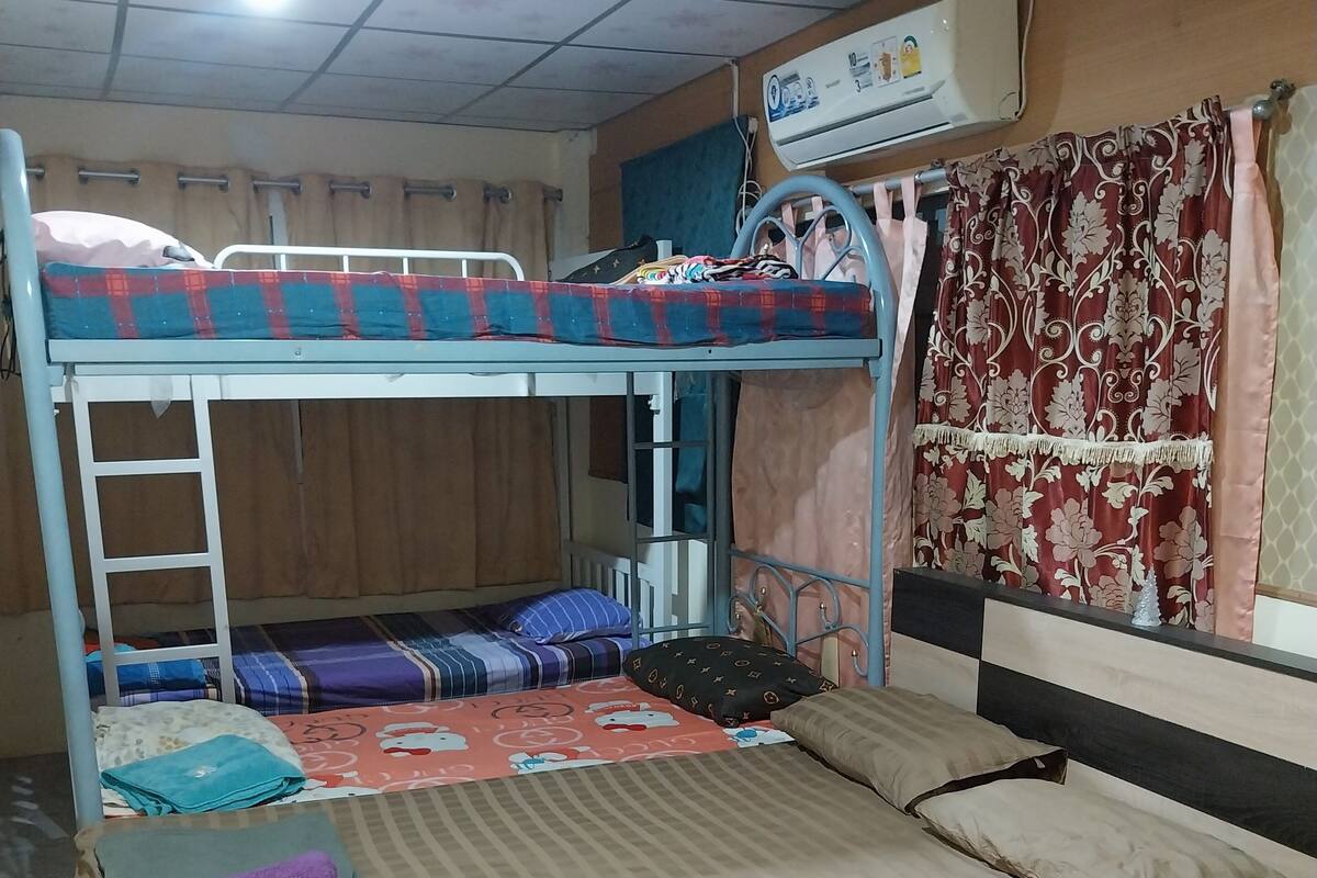 Habitación con literas, ventilador de techo y aire acondicionado, además de una cortina.