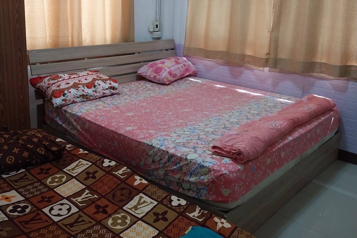 Un dormitorio con cama, mesita de noche, armario y cortinas.