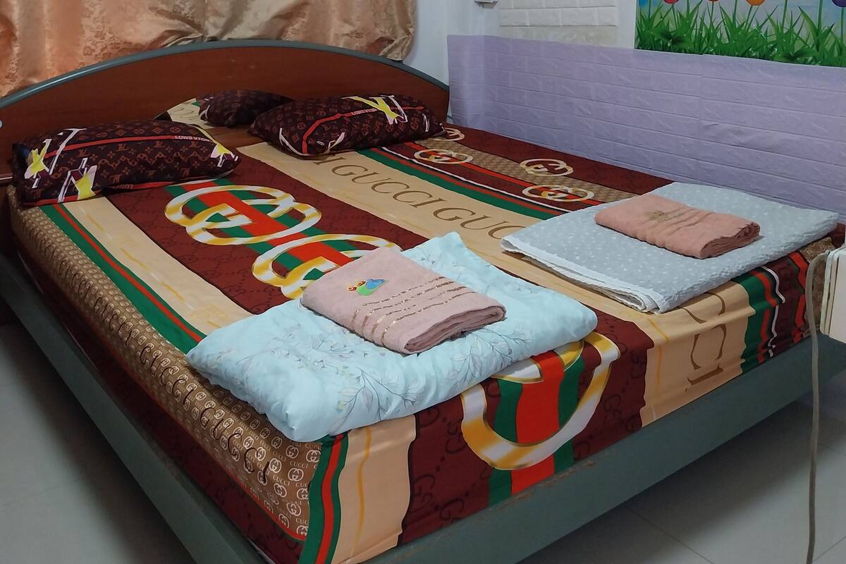 Una cama con una colcha estampada, dos almohadas y una manta.