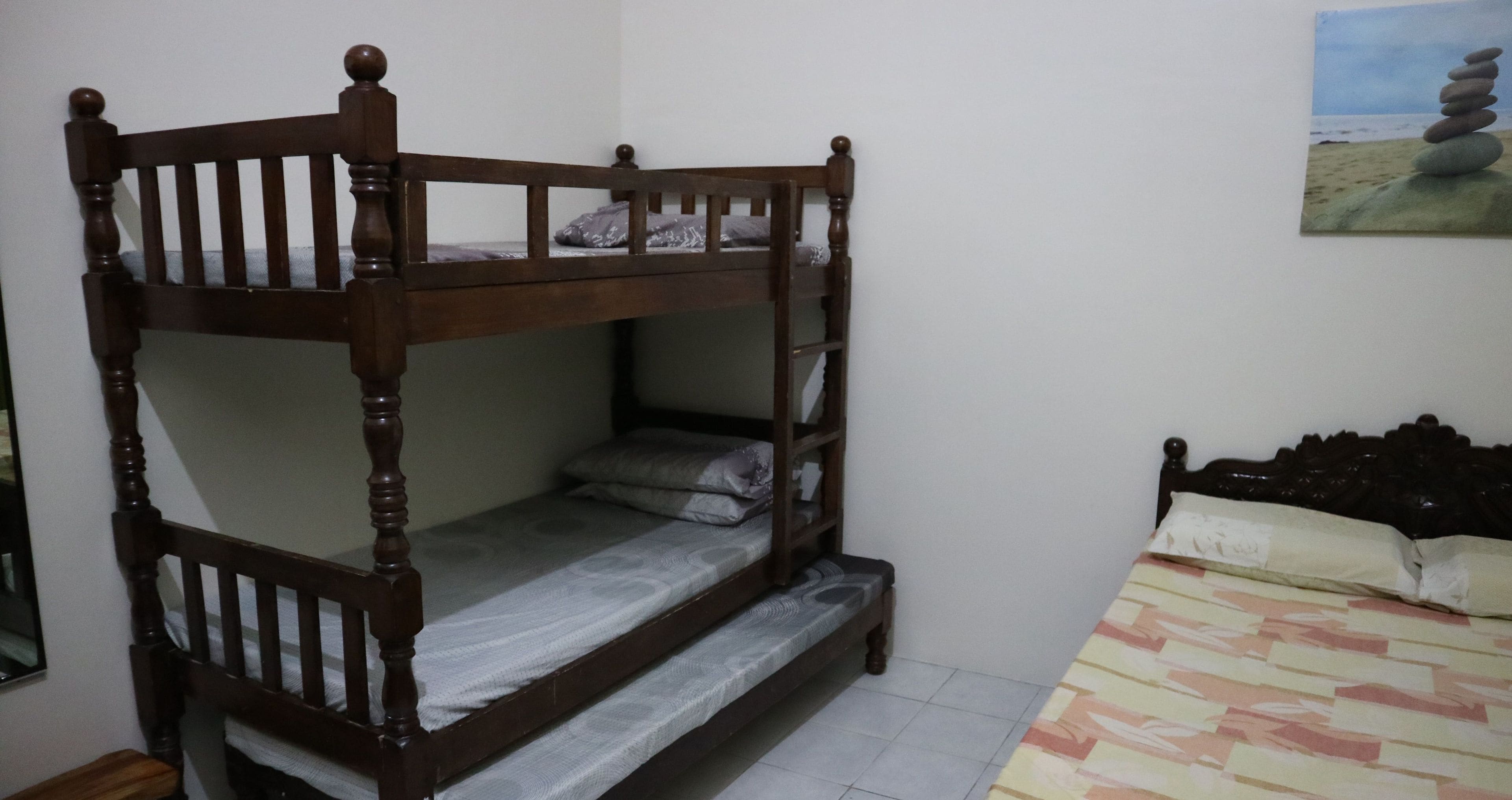 Un lit superposé avec une structure en bois et un lit inférieur recouvert d’une couvre-lit à motifs.
